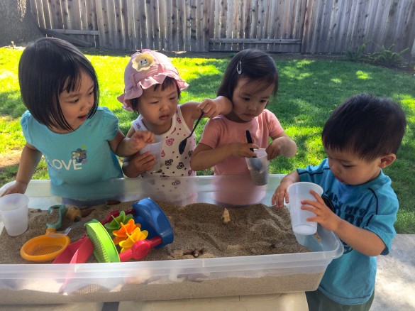 Natty, Roxy, Karis, and Austin playing with sand in a box