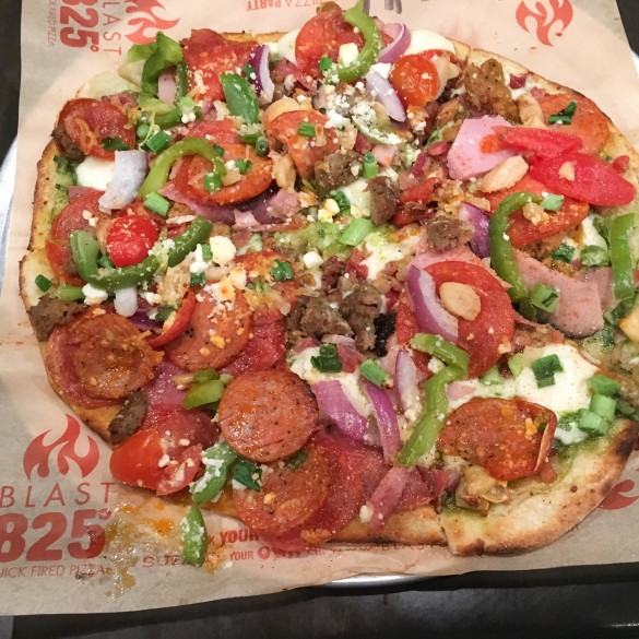 Kenny's pizza with pesto, pepperoni, salami, sausage, bacon, linguisa, shredded and fresh mozzarella, roasted garlic, fresh tomatoes, red onion, green peppers, feta, and parmesan cheese