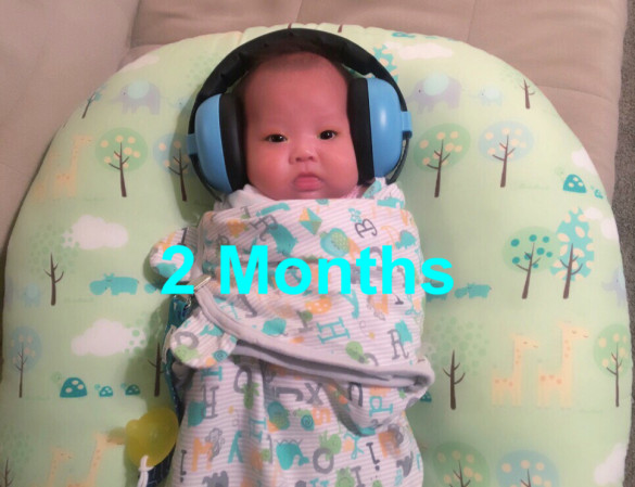 Carissa with her new Baby Banz noise canceling headphones at 2 months