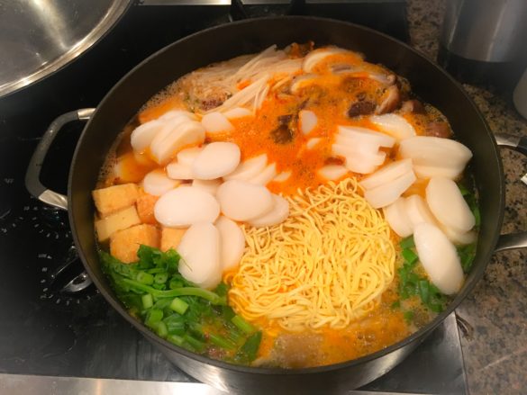 Budae Jjigae with the addition of instant ramen noodles, rice cakes, and green onion, 