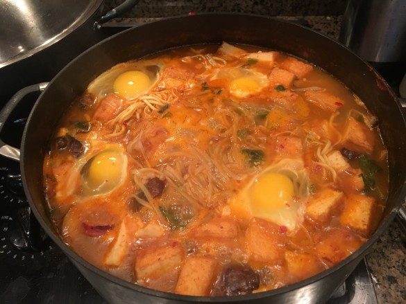 Budae Jjigae with the addition of freshly cracked eggs and sausage